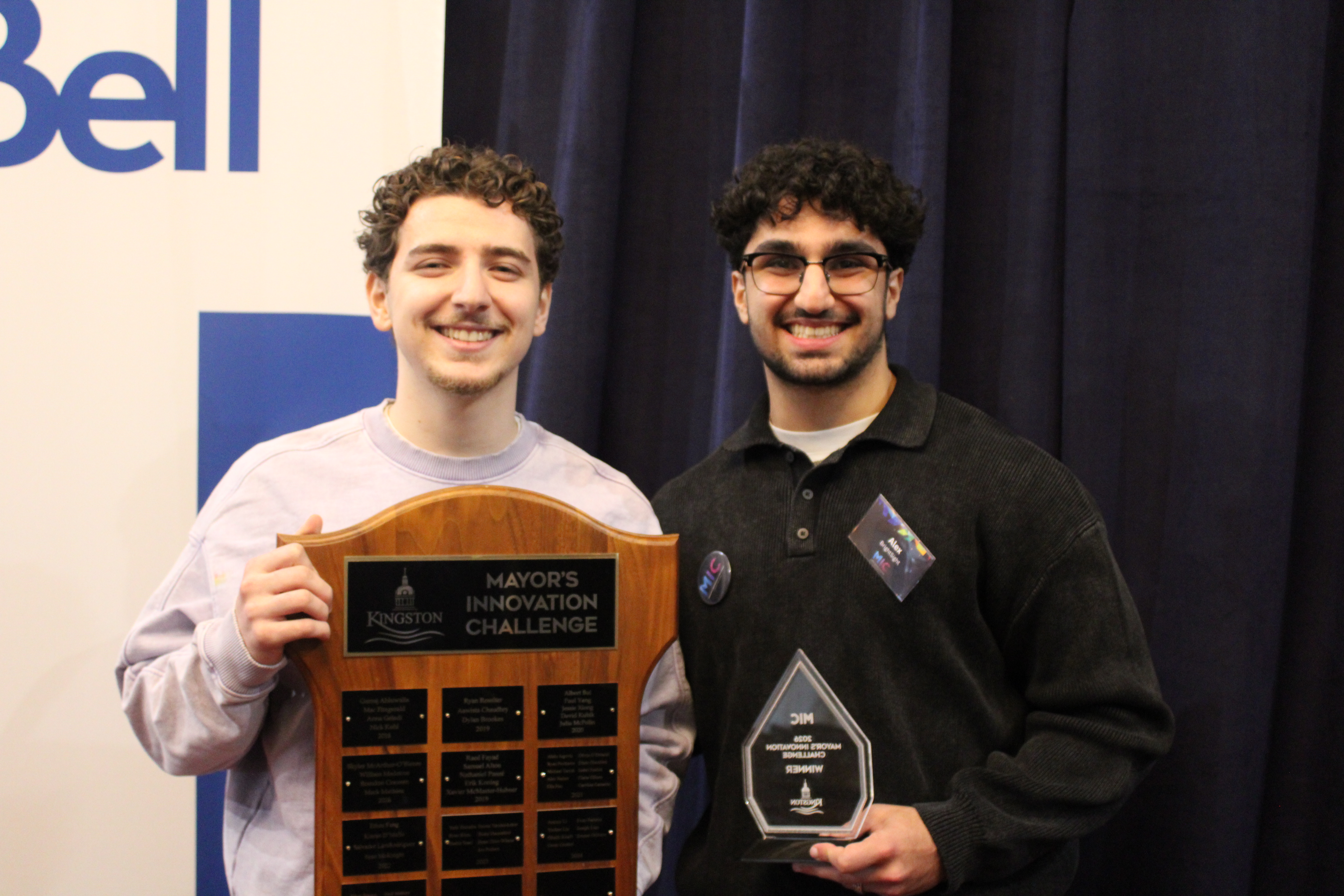 Two Queen's University students holding a plaque and trophy for the Mayor's Innovation Challenge.