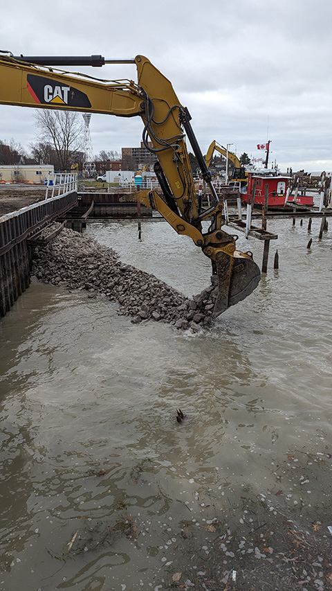 backhoe placing gravel in water