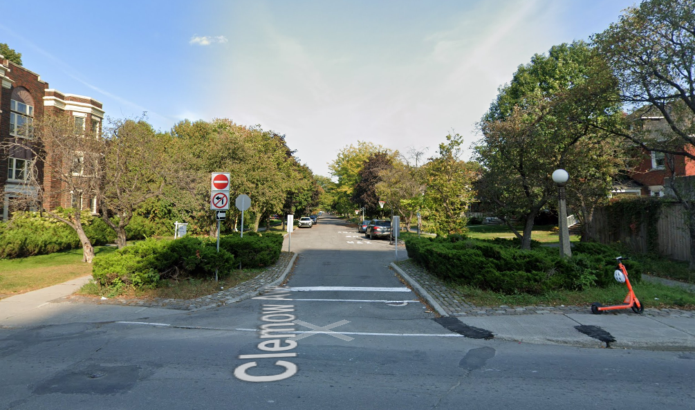 Photo shows one lane to access a street. Wide spaces between the lane and the sidewalk are filled with bushes.