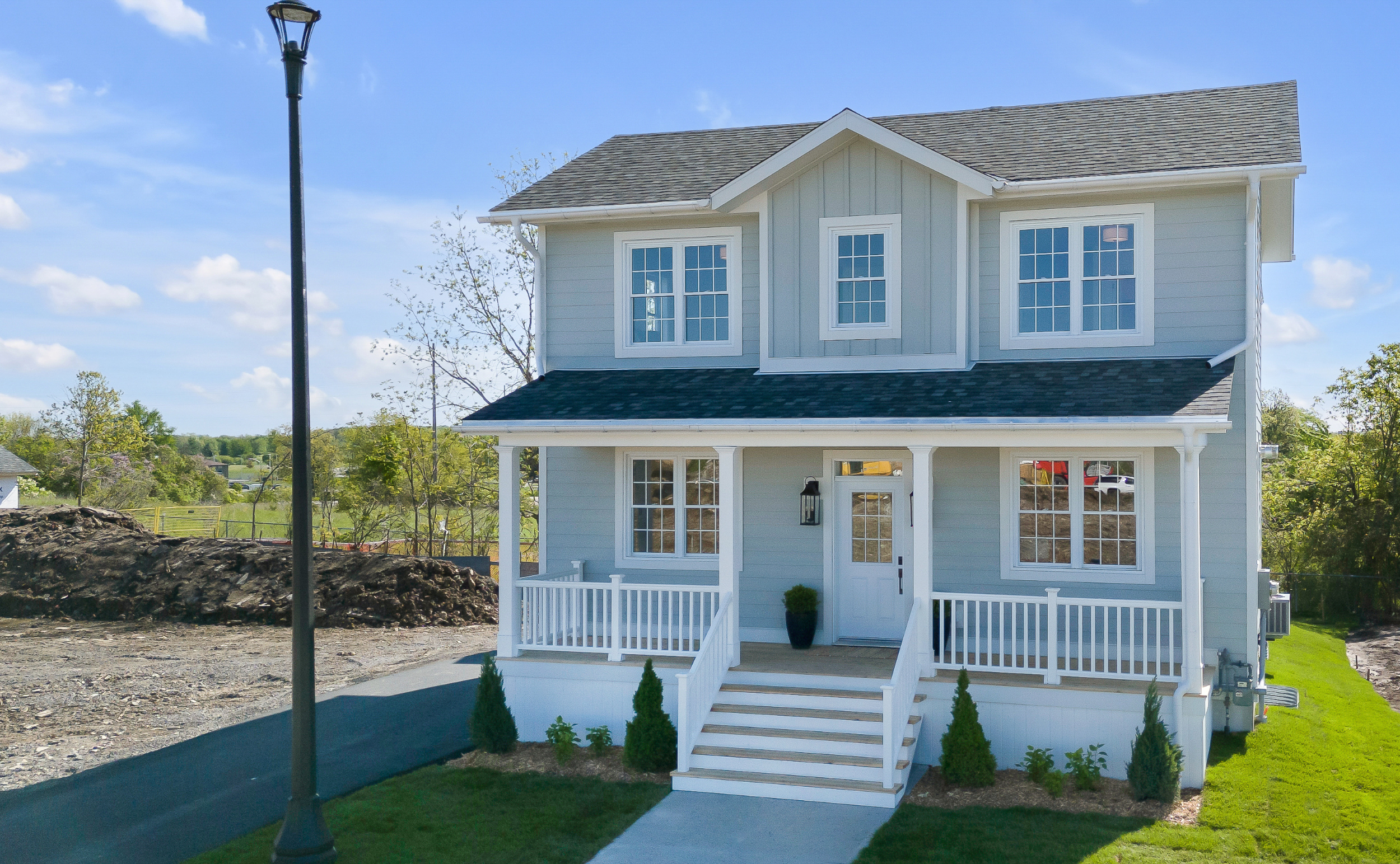 photo of 276 Old Kiln Crescent - a new home with two storeys and a porch across the front of the house. The house is light blue/green with a gray roof and white windows and door.