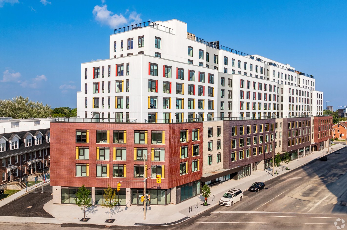 A large apartment building with multiple colours of brick on the lower floors and white stone upper floors. 