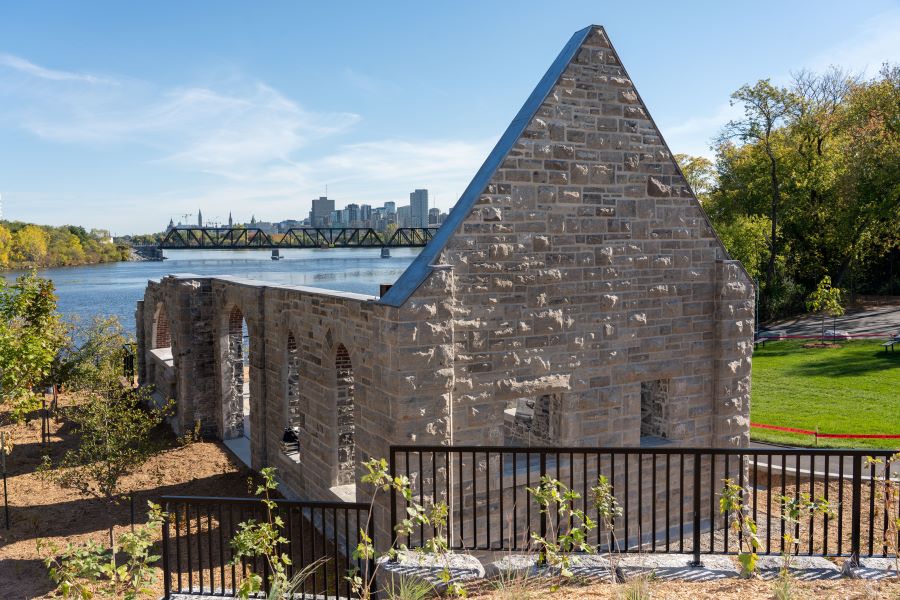 Close up of Hintonburg heritage pumphouse stone walls with Ottawa River and downtown Ottawa in the background at opening event on October 2, 2025.