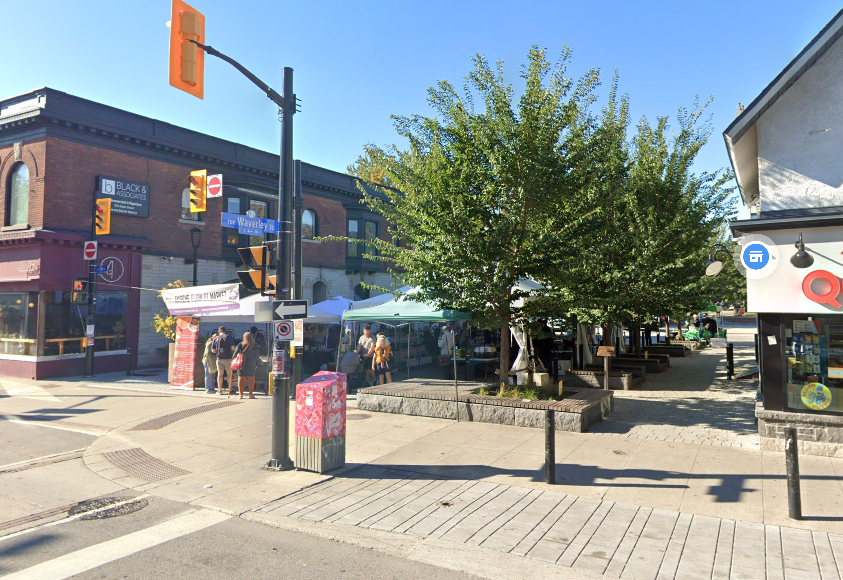 Public space with trees and market stalls set up temporarily.