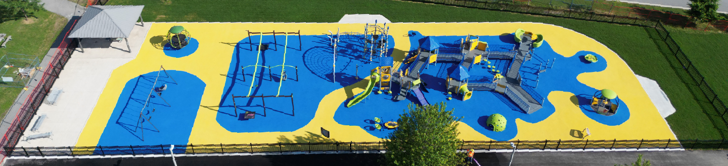 aerial view of the jumpstart inclusive playground with yellow and blue safety flooring and a variety of inclusive play structures