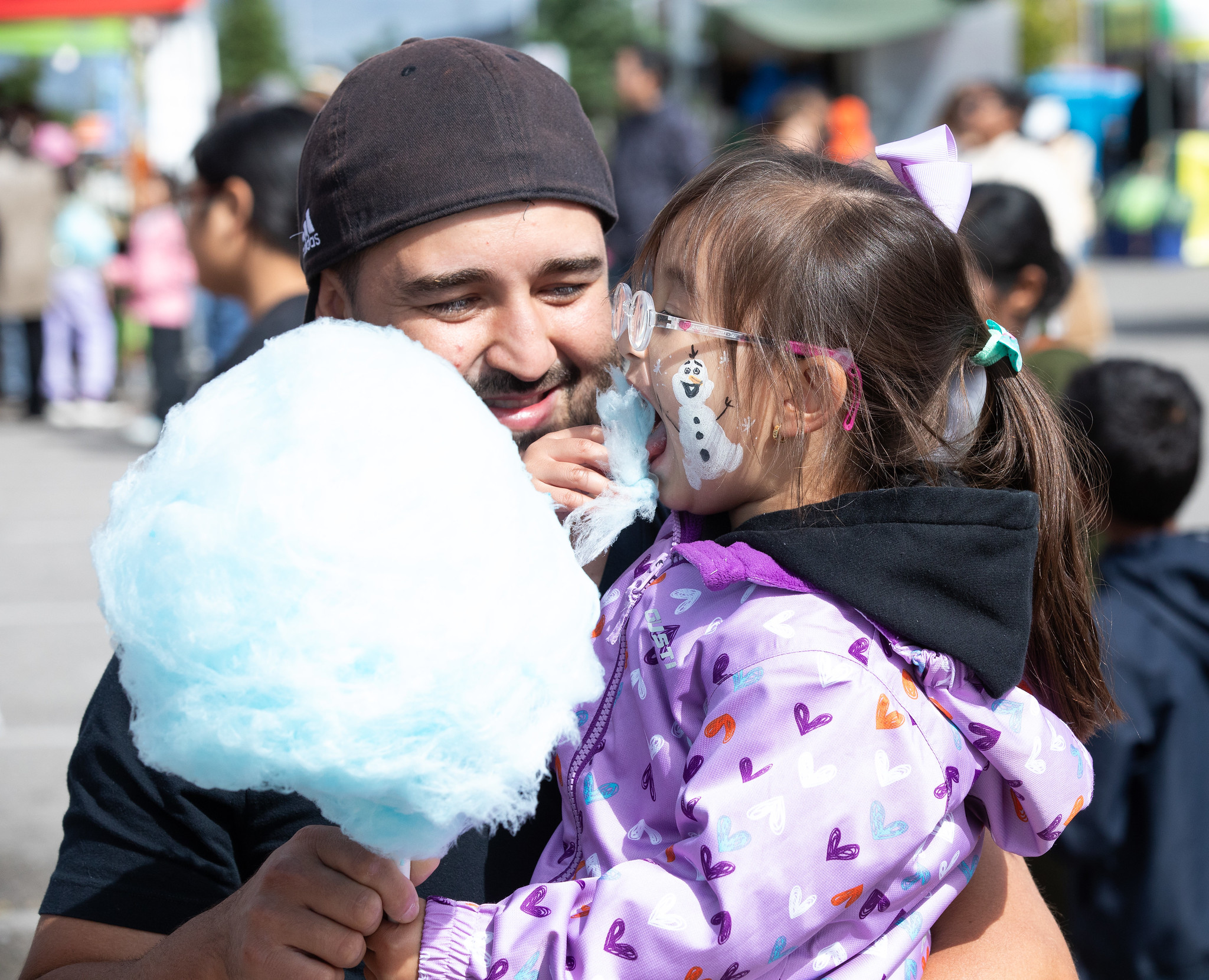 Child and their parent eating cotton candy.