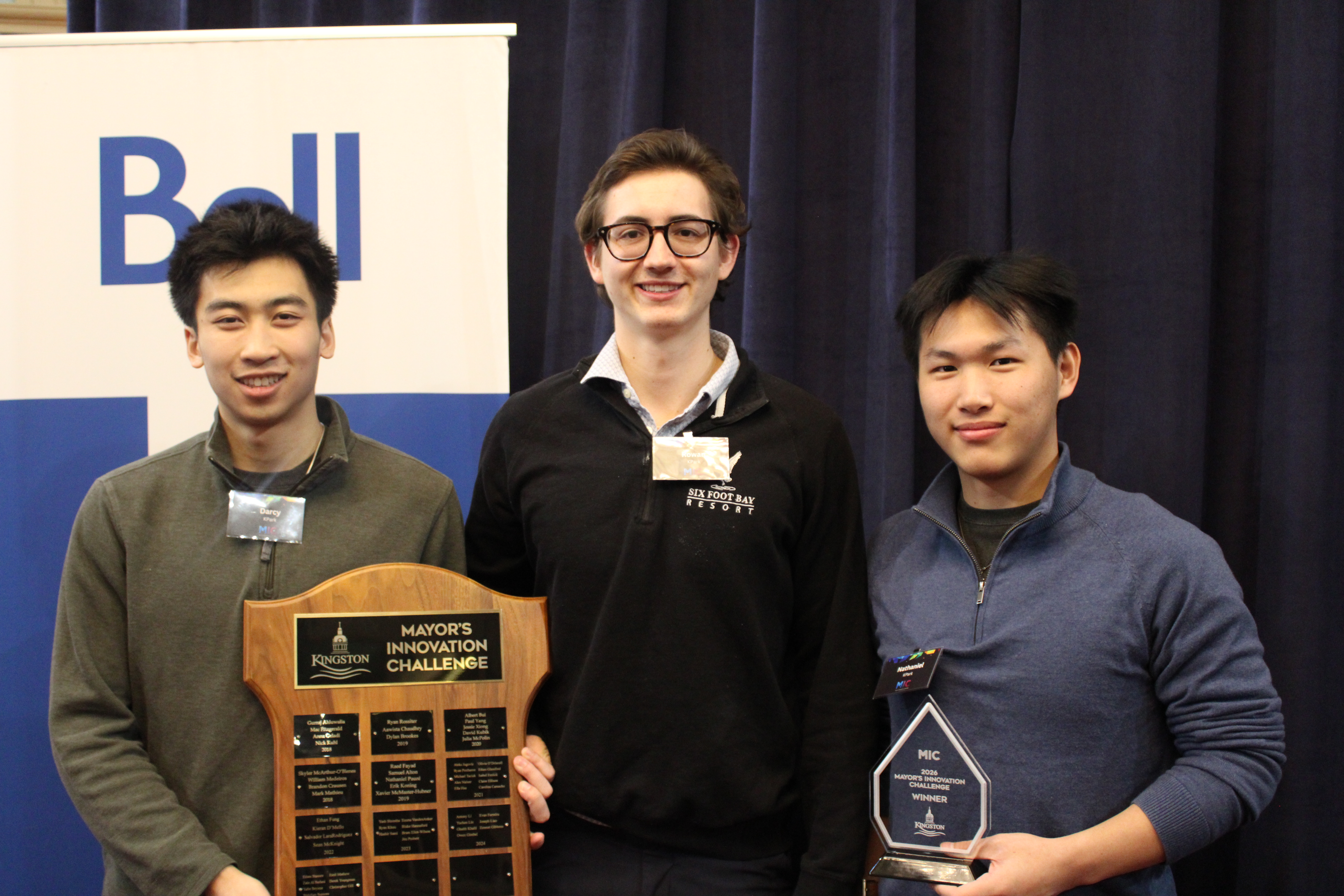 Three Queen's University students holding a plaque and trophy for the Mayor's Innovation Challenge.