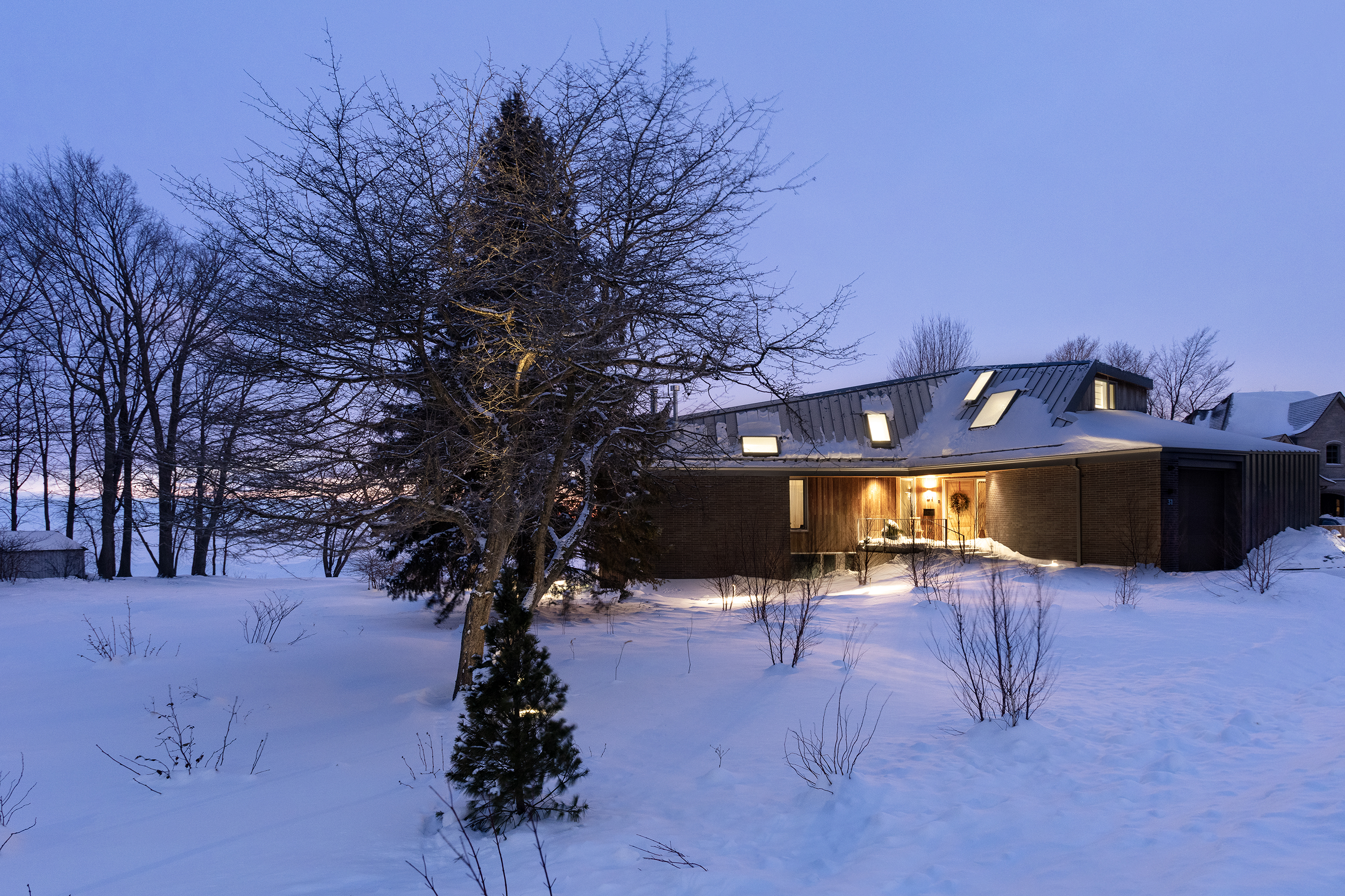 Nighttime view of a home at 31 Point Crescent. The home features creative angles and windows. 