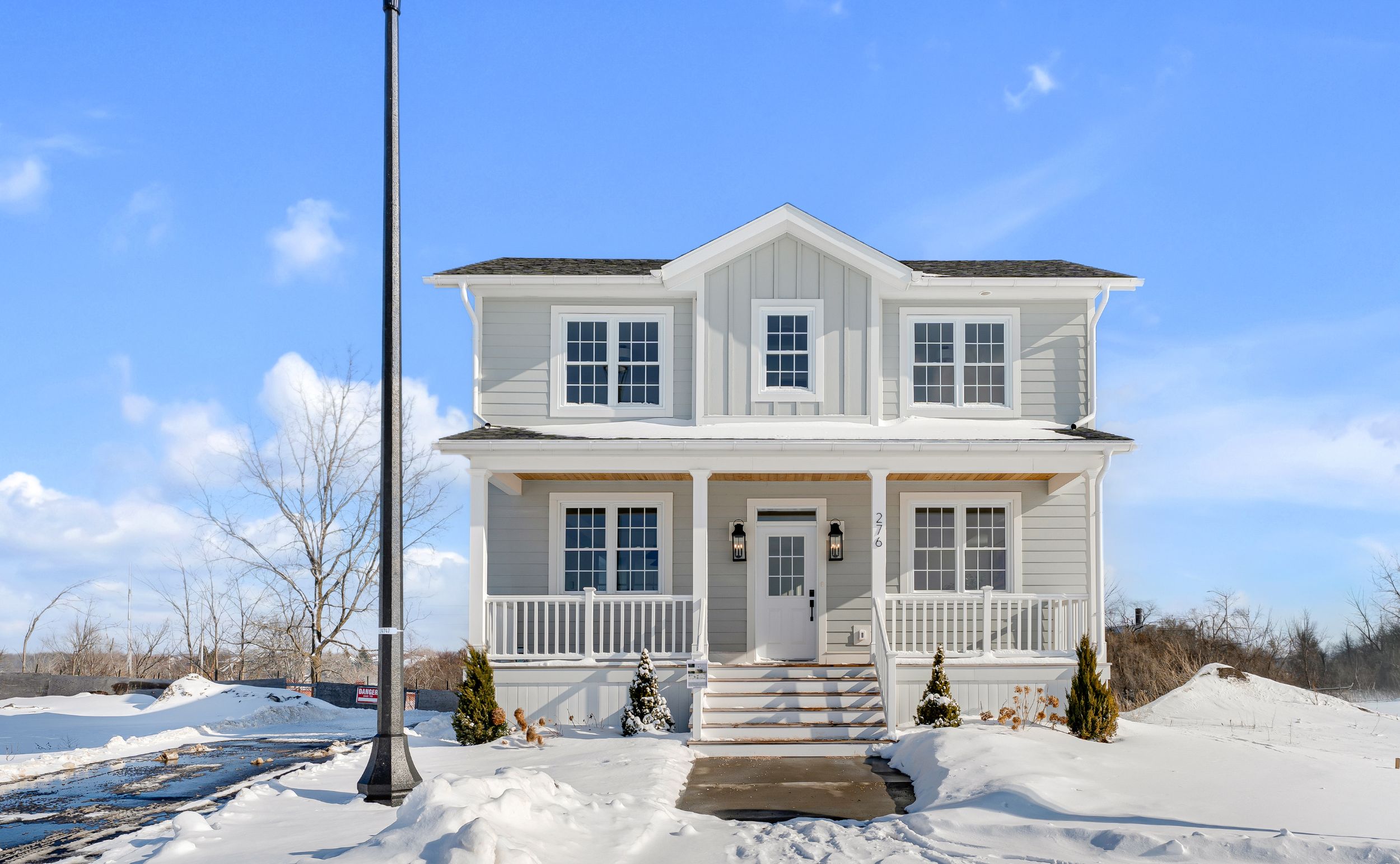 A model home at 276 Old Kiln Crescent. The home has gray siding and is symmetrical, with a roofed porch. 