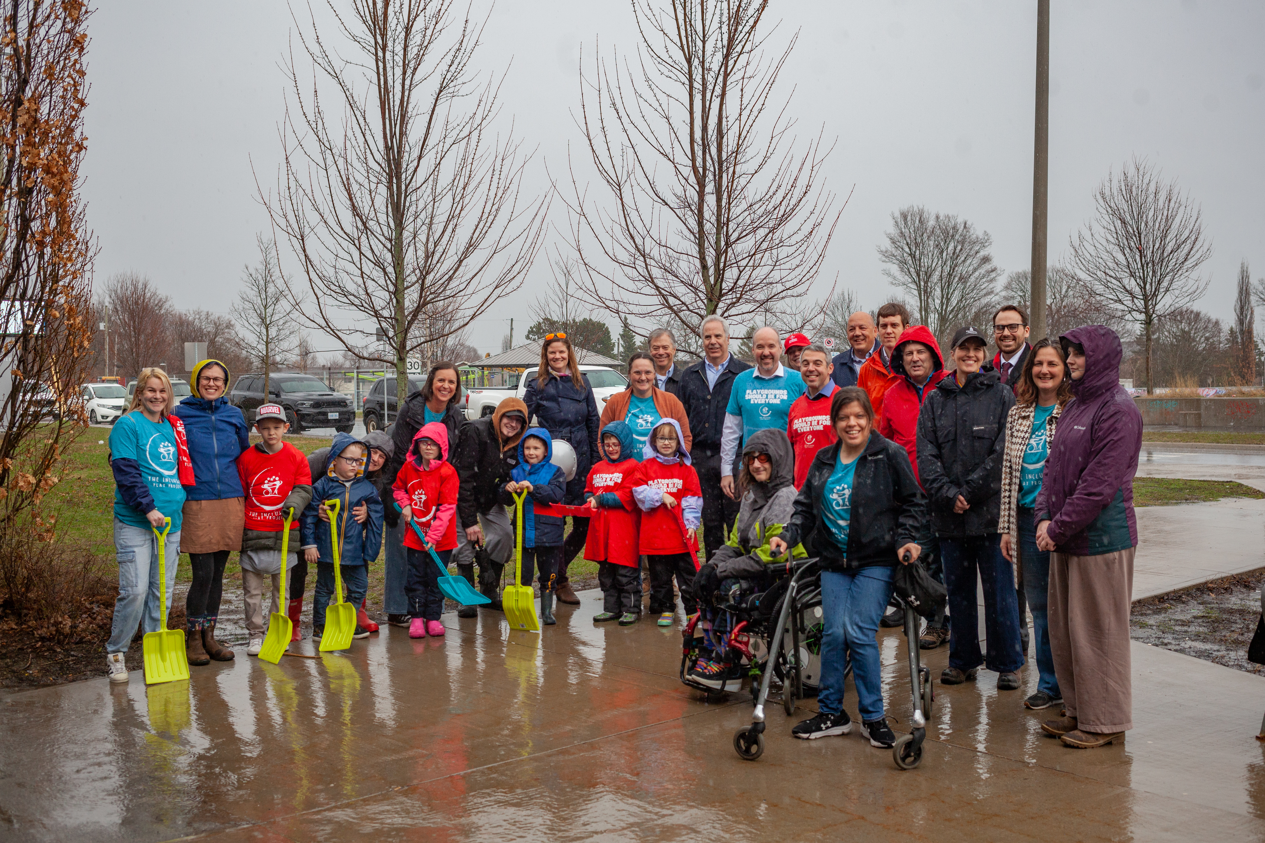 A photo a a group of people holding shovels in front of the future playground site.
