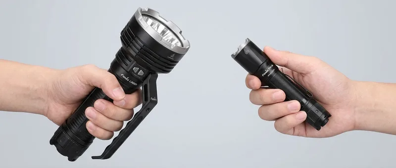 A large Fenix LR80R searchlight beside a compact Fenix TK16 tactical flashlight, showing the size difference