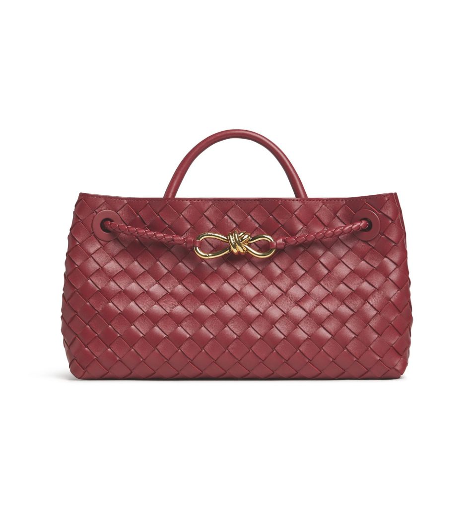 Red textured handbag with a gold bow detail on the handle.