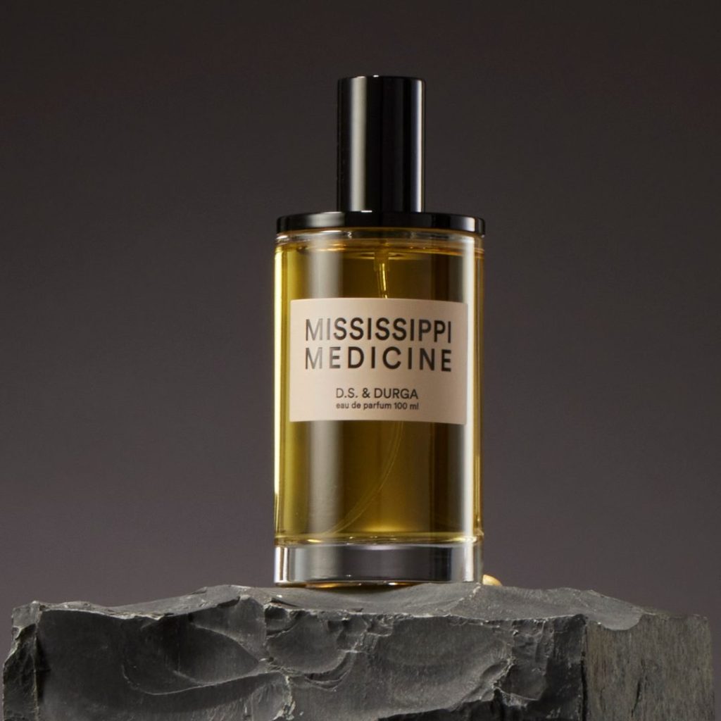 Transparent perfume bottle with dark yellow liquid and tan Mississippi Medicine label.