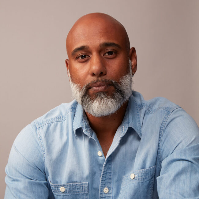 Muraly Srinarayanathas, founder and publisher of Three Magazine, portrait with a light blue shirt, showcasing a thoughtful expression, against a neutral background.