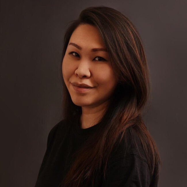 Partnerships & Editorial Strategy Director Dara Chau, smiling portrait with dark background, reflecting multicultural identity and collaboration in Three Magazine.