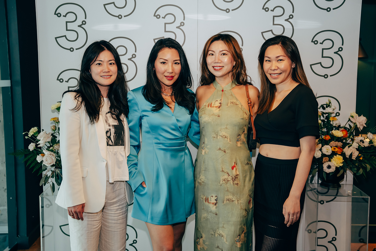 Four women posing together at a 3 Magazine summer event, featuring stylish outfits and a floral backdrop with the magazine's logo.