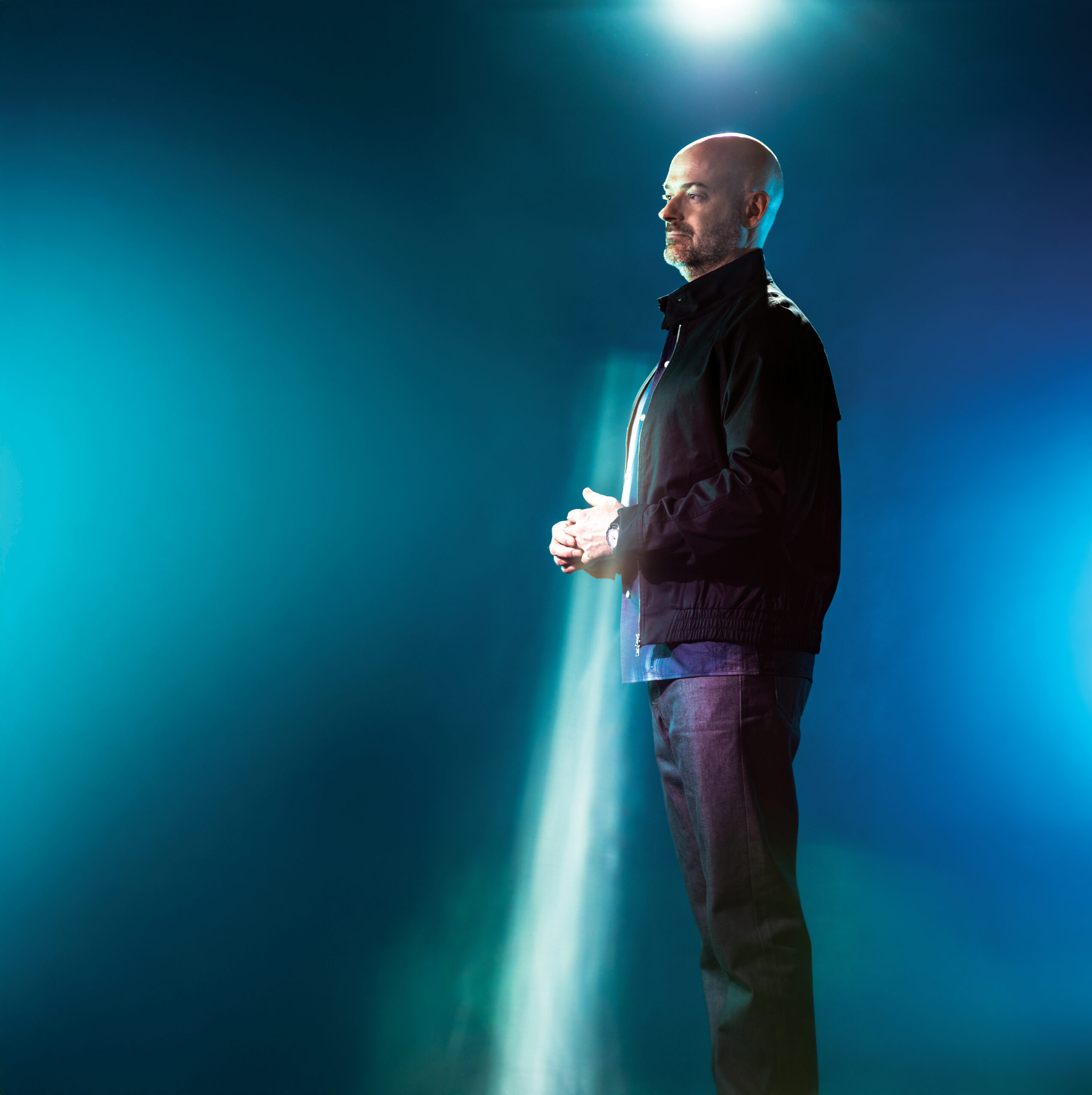 Man standing in profile against a blue and green illuminated background, showcasing a modern aesthetic relevant to technology discussions.