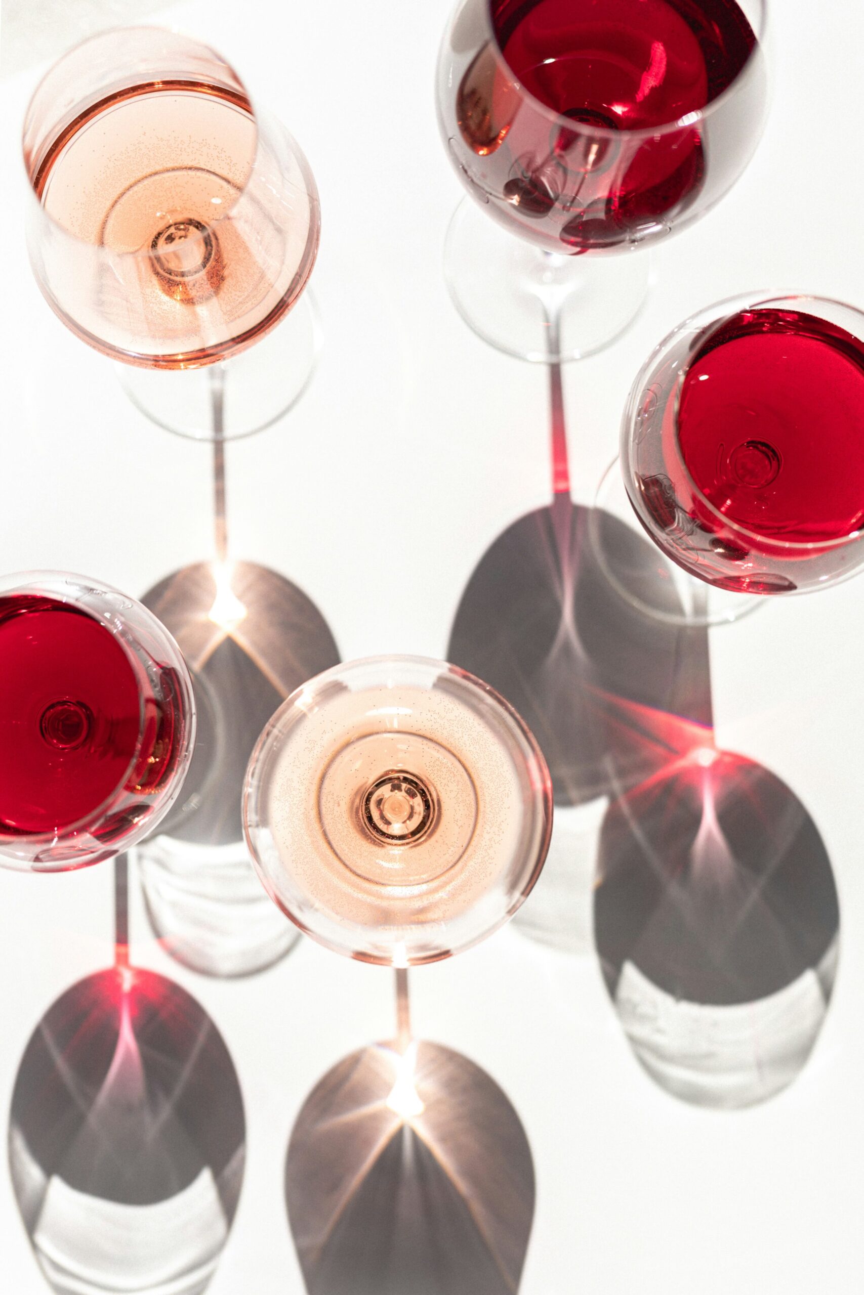 Glasses of red and ros&eacute; wine casting intricate shadows, reflecting the exploration of emerging wine regions discussed in Shetu Modi's article.