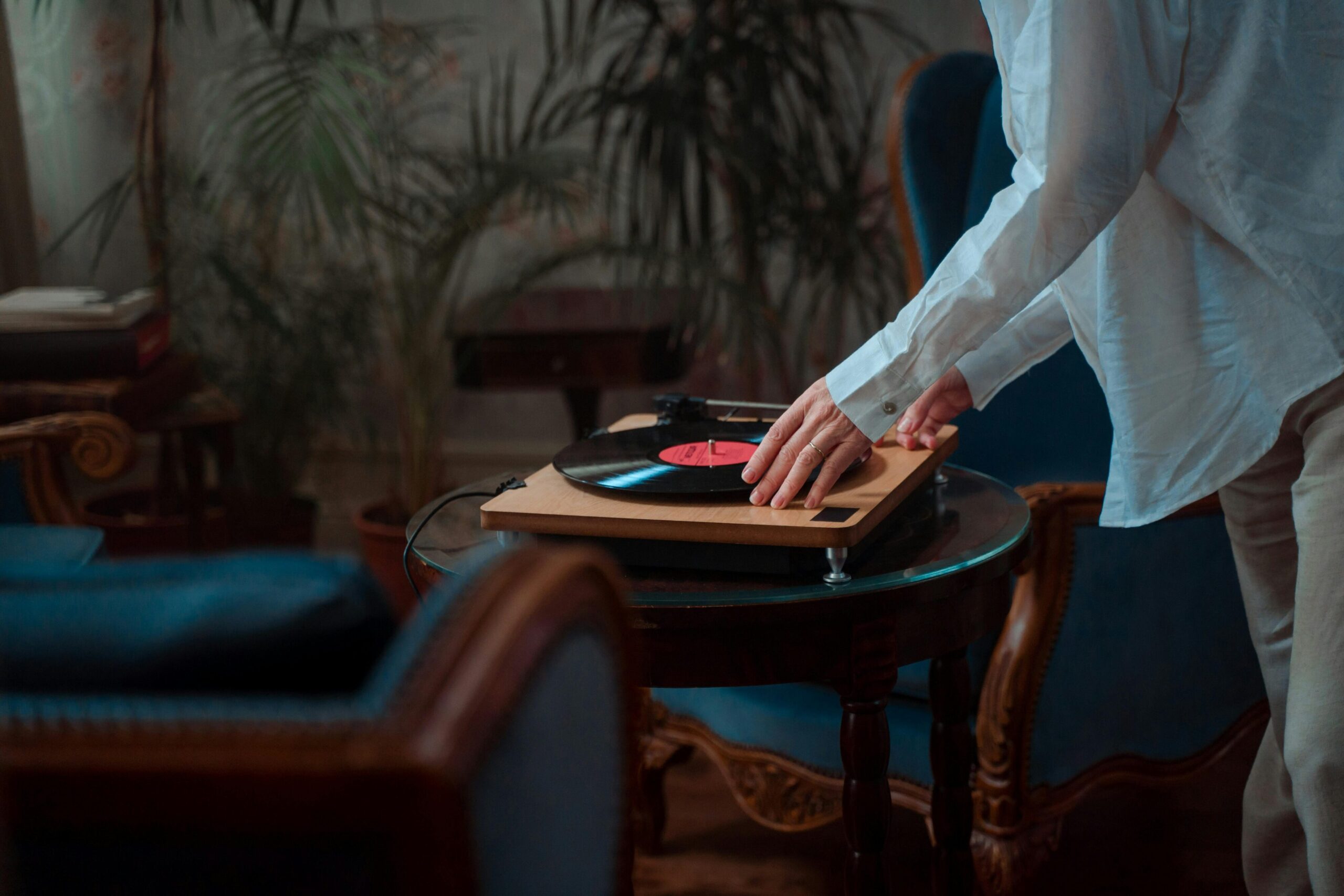 Person placing a vinyl record on a turntable in a cozy interior setting, highlighting the resurgence of vinyl culture amidst discussions on luxury and design.