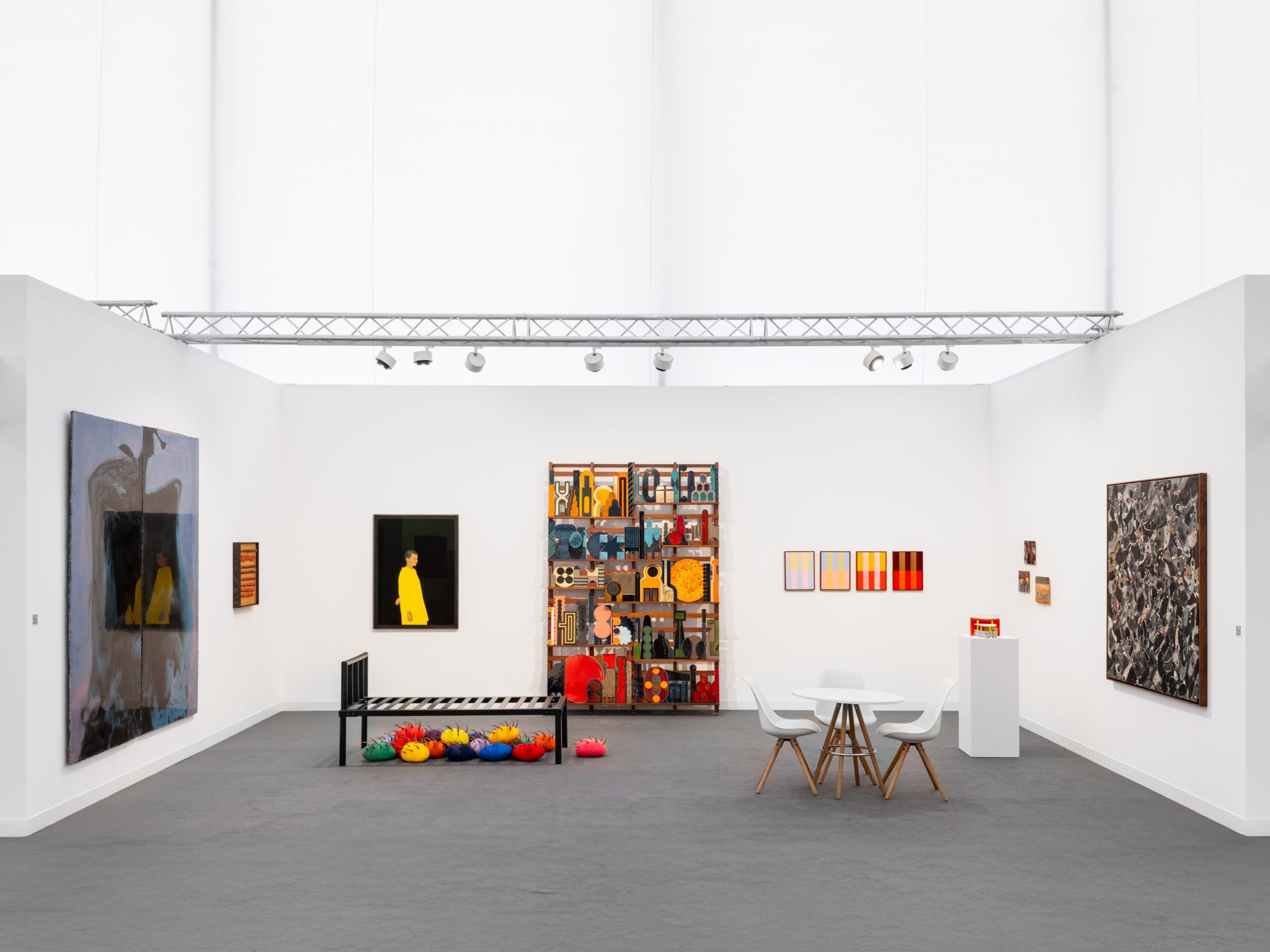 Installation view of contemporary art exhibition featuring vibrant paintings and sculptures, highlighting the intersection of fashion and art in a modern gallery setting.