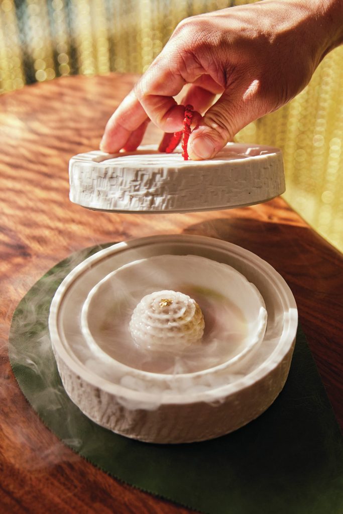 Close up of a person opening a ceramic dish that reveals a large dumpling.