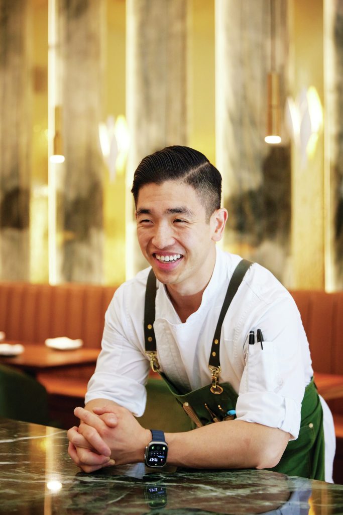 Chef Eric Chong smiling in the dining room of his restaurant.