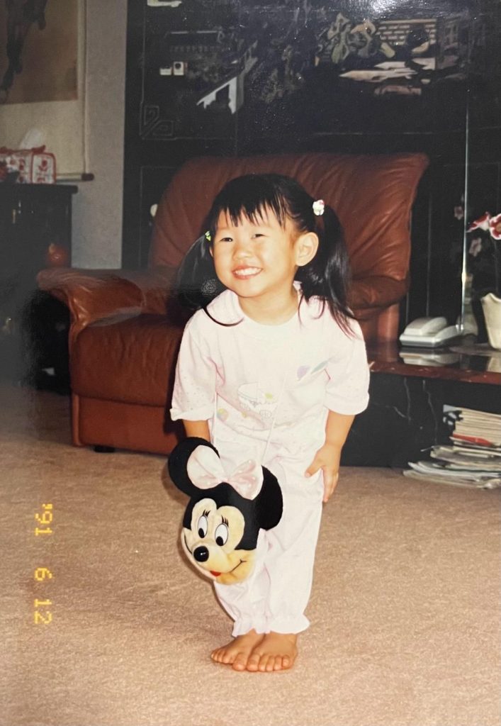 Evelyn Chick as a young child holding a Minnie Mouse plush toy.
