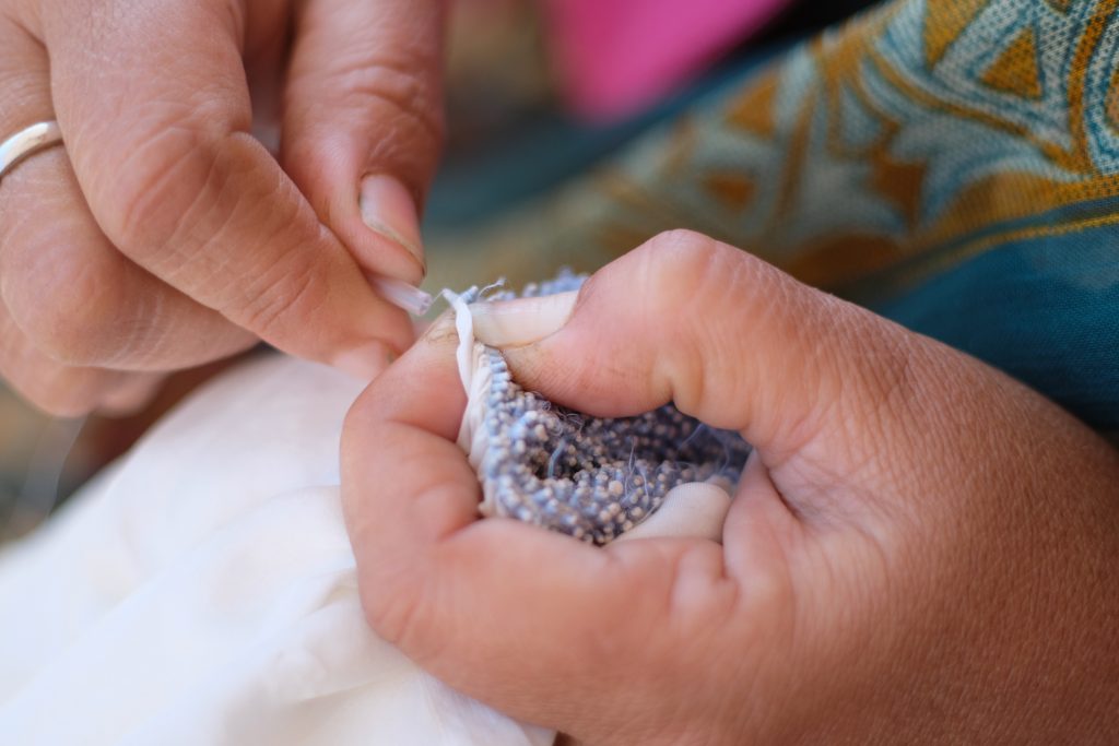 Close up of hands weaving fabrics.