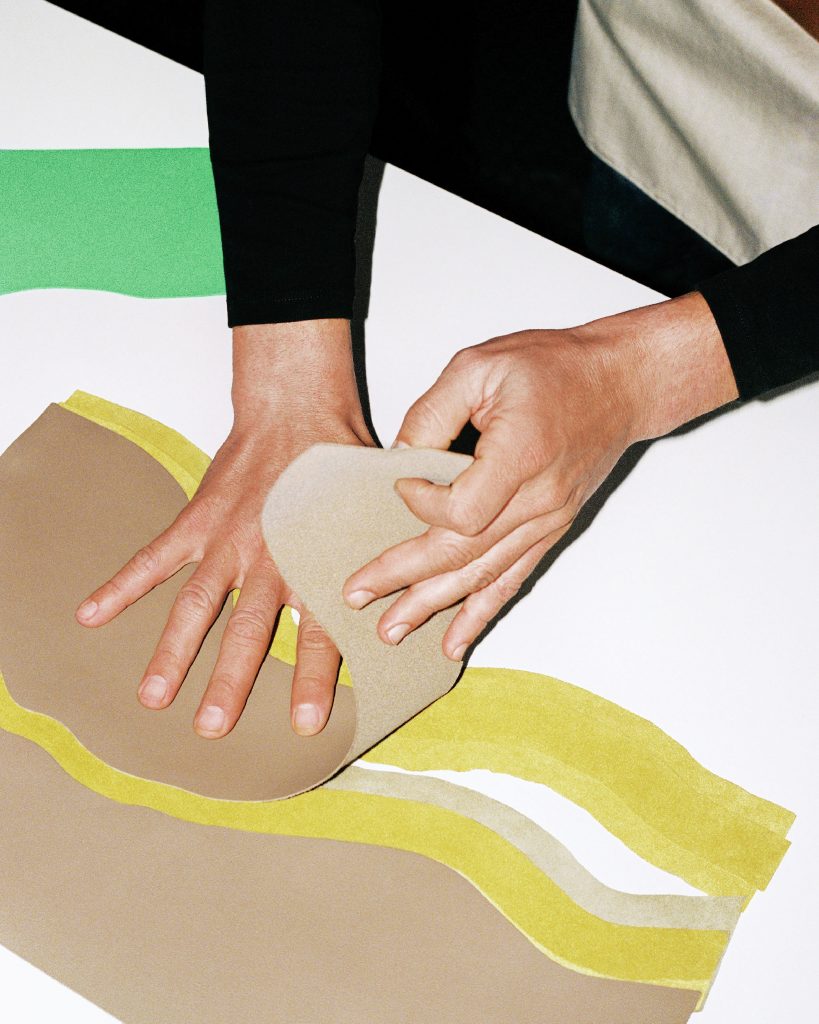 Close up of hands working with beige, yellow and light green leather pieces.