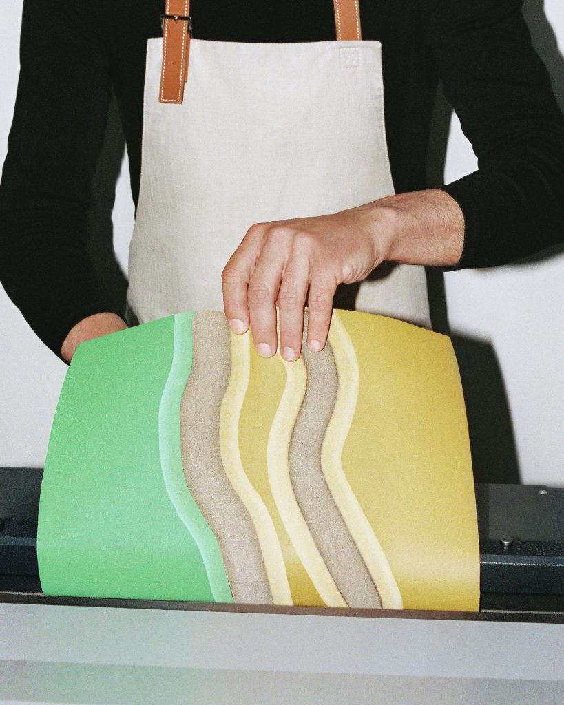 Person lifts the leather design to reveal a light green, beige and yellow pattern.