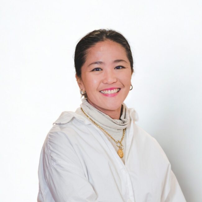Ashley Pang, Events and PR Director at Three Magazine, smiling in a white outfit, surrounded by a bright background.