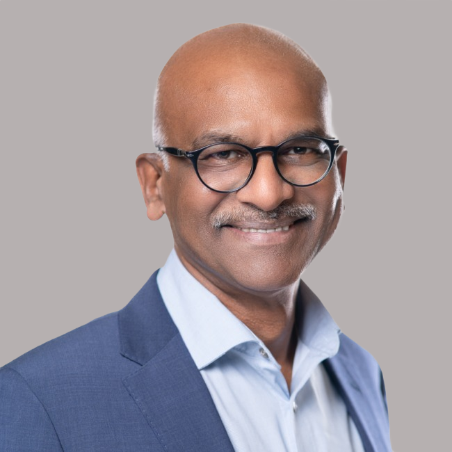 Dinesh Kumar, advertising sales professional, smiling in a suit against a neutral background, representing Three Magazine's diverse contributors and global cultural narrative.