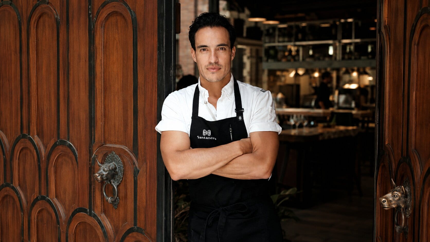 Chef Andrés Becerra standing in a restaurant wearing a black apron
