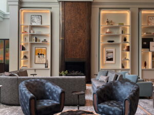 Hotel lobby with fireplace, illuminated bookshelves and blue lounge chairs