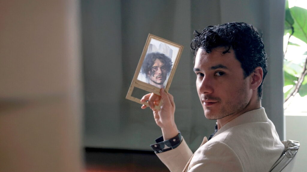 Brendan Fitzpatrick holding a handheld mirror while seated in a chair