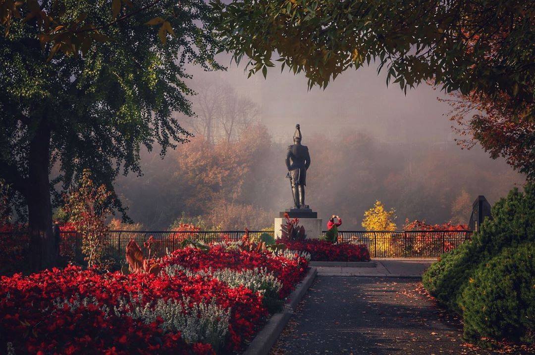 Photo gagnante du concours Instagram de 2019 prise au parc Major's Hill. On y voit une platebande aux fleurs rouges et la statue du Colonel John-By sur un fond d'automne brumeux.