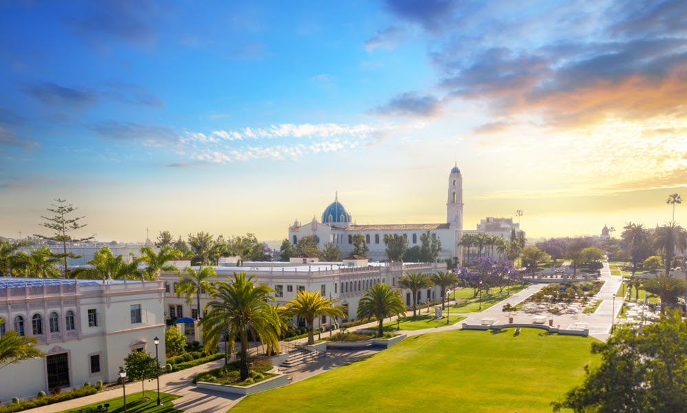 Wide-angle view of the iconic blue mosaic dome and Spanish-Renaissance architecture of The Immaculata Church at the University of San Diego campus during sunset.