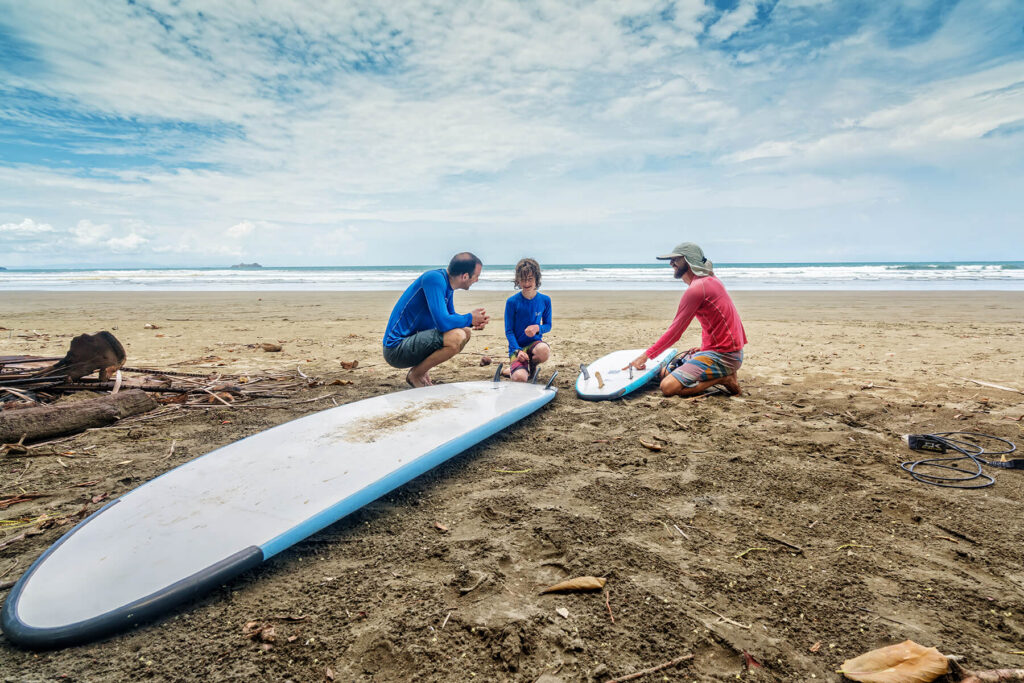 A Bodhi surf instructor teaching surf literacy and ocean safety to a family on the beach in Bahia Ballena.