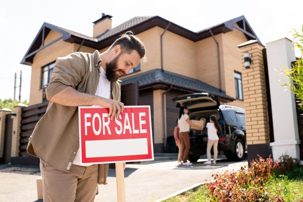 A man pulling out the for sale sign in his new home.