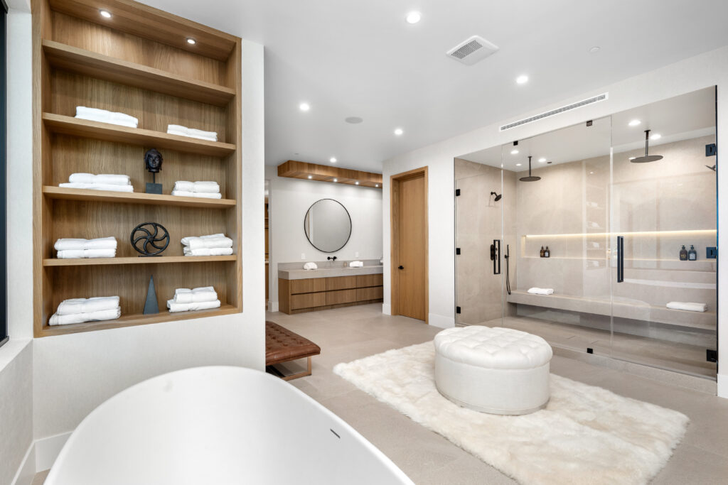 A modern all-white bathroom with wooden shelf and flooring.