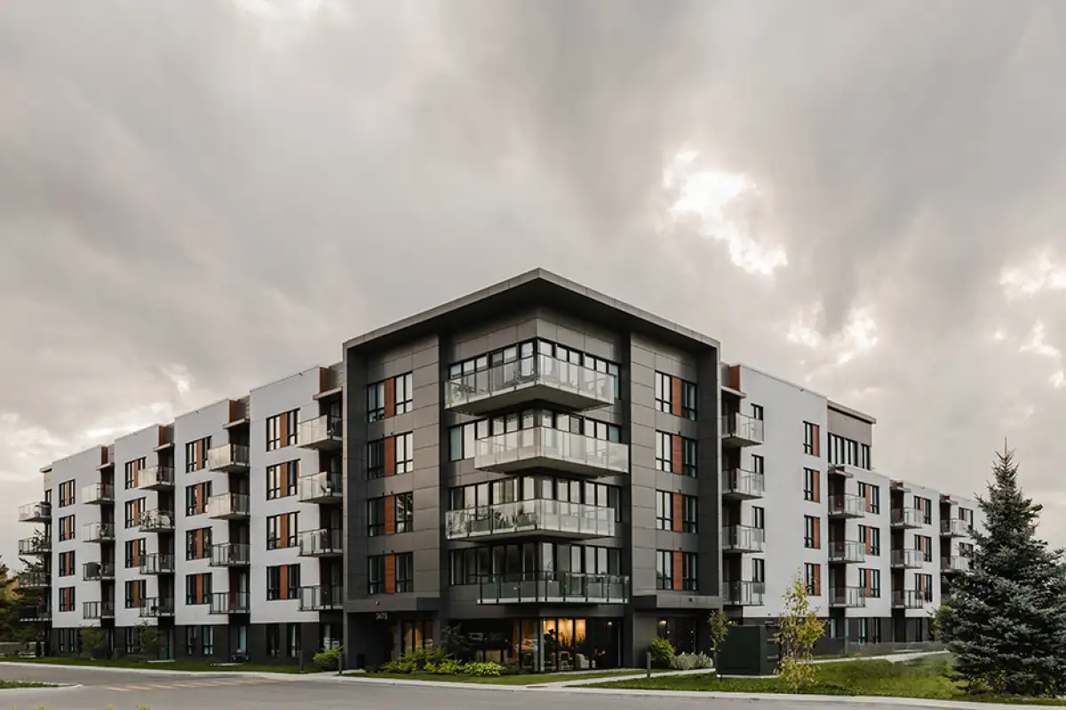 Immeuble résidentiel moderne à plusieurs étages avec balcons, sous un ciel nuageux