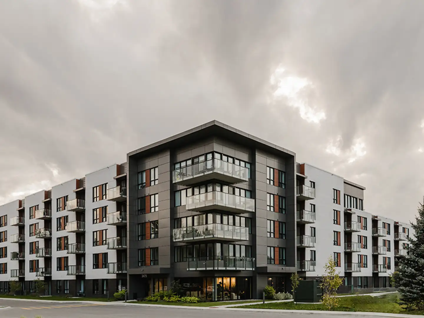 Immeuble résidentiel moderne à plusieurs étages avec balcons, sous un ciel nuageux