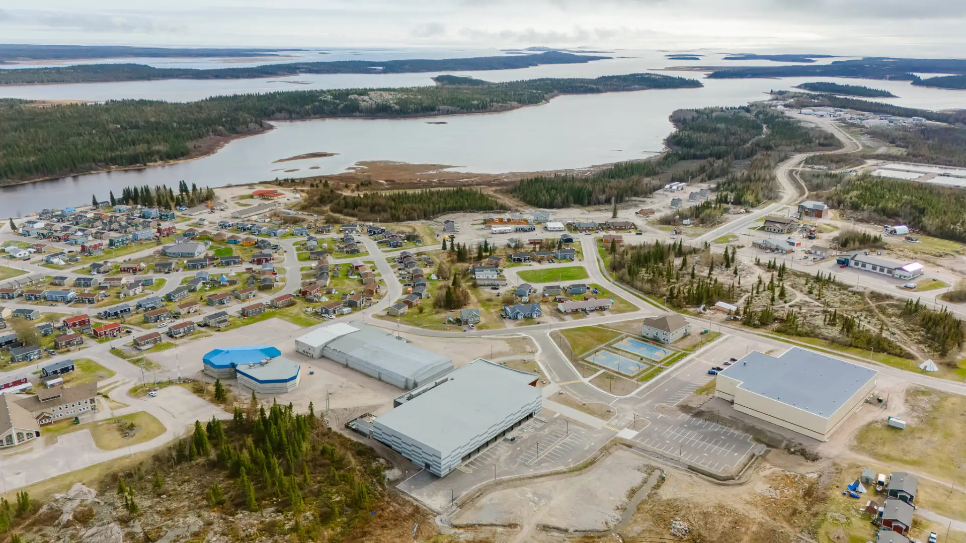 Vue de l’aréna de Wemindji à vol d’oiseau : un bâtiment moderne à proximité de sa communauté et de la nature environnante.