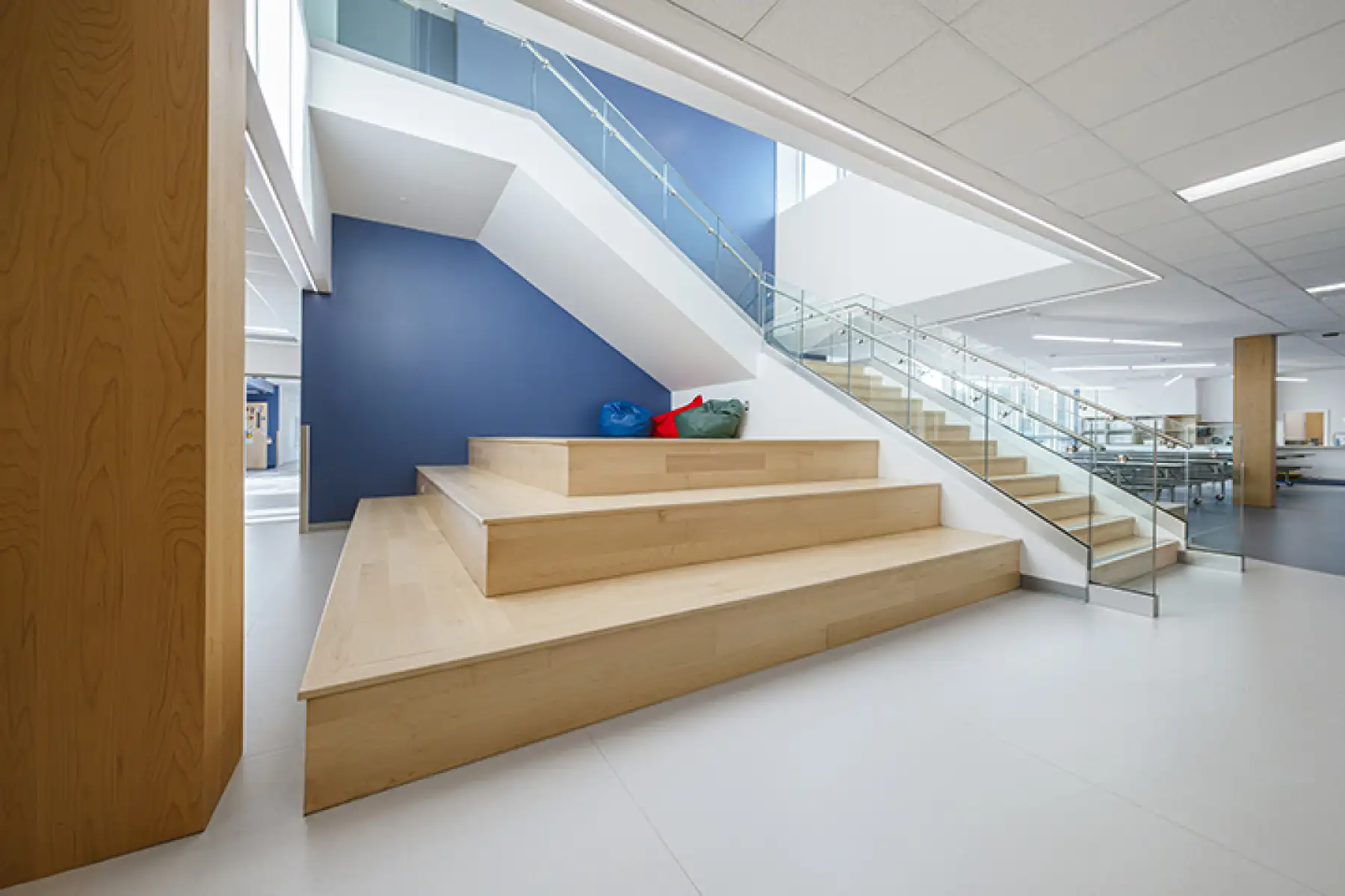 Escalier central avec gradins intégrés dans l’aire commune de l’École des Deux-Rivières, architecture scolaire moderne favorisant la collaboration et l’apprentissage.
