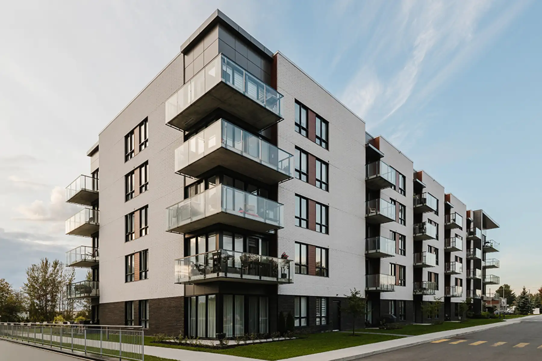 Immeuble résidentiel moderne avec balcons en verre, photographié depuis la rue