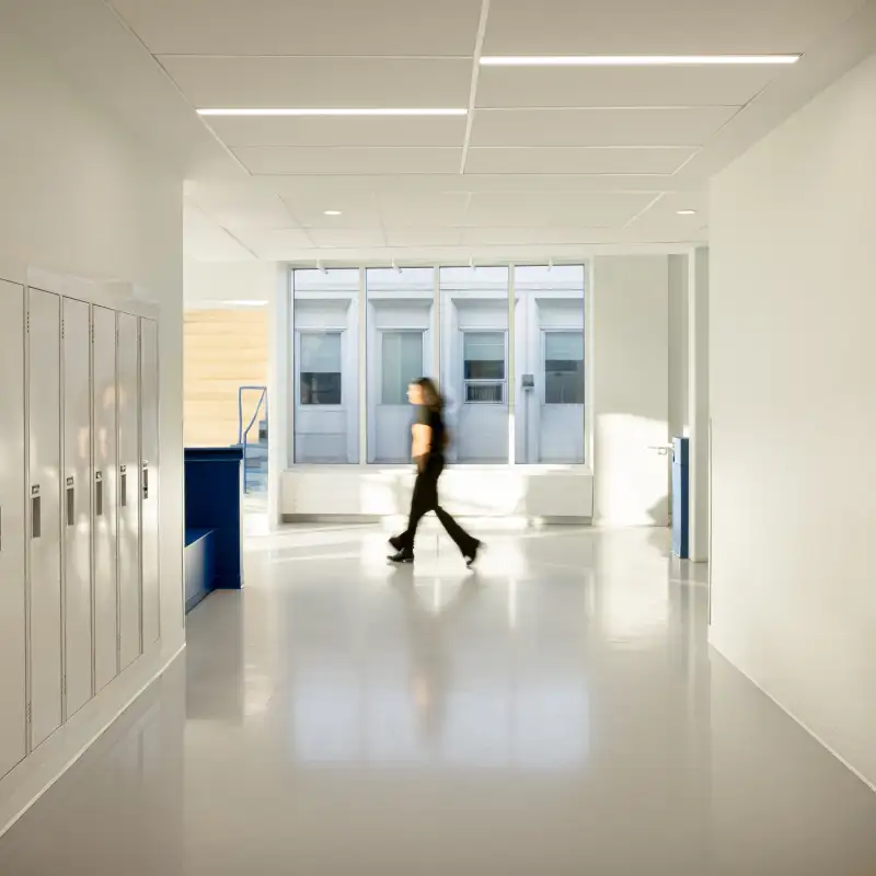Corridor lumineux de l’École Cardinal-Roy avec casiers intégrés, grandes fenêtres et circulation fluide au sein d’un environnement d’apprentissage moderne.