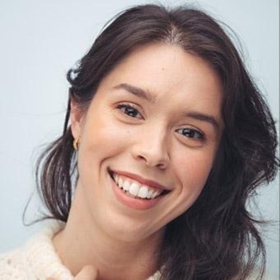 Portrait d'Audrey Perreault, une femme au teint clair, aux yeux bruns et aux longs cheveux bruns. Elle affiche un grand sourire en regardant la caméra.