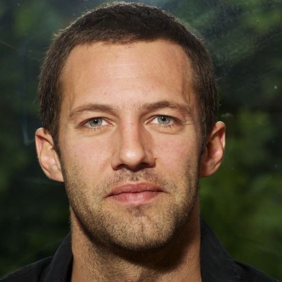 Portrait de Martin Vaillancourt, un homme au teint clair, aux yeux bleu-vert, aux cheveux bruns courts ayant une barbe courte. Son visage est détendu et il regarde l'objectif.