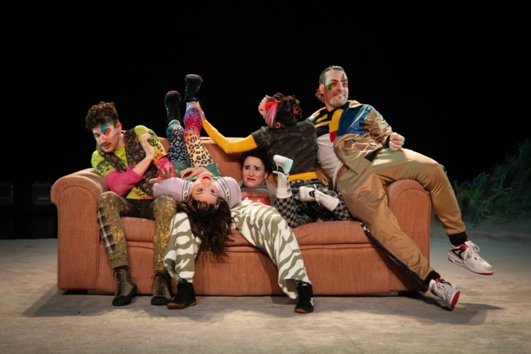 Cinq personnages prennent différentes poses sur un divan : à l'endroit, de dos, couché sur le dos, les jambes écartées. Tous les personnages portent des vêtements colorés et à motifs variés, et ont des visages expressifs.