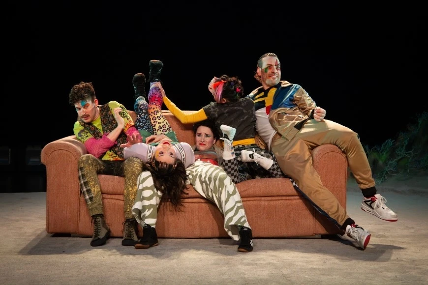 Cinq personnages prennent différentes poses sur un divan : à l'endroit, de dos, couché sur le dos, les jambes écartées. Tous les personnages portent des vêtements colorés et à motifs variés, et ont des visages expressifs.
