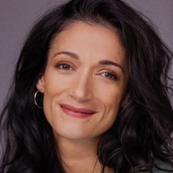 Portrait de Laurie Gagné, une femme au teint moyen clair, aux yeux bruns et aux longs cheveux foncés. Sa tête est légèrement incliné vers la droite et elle regarde la caméra en souriant.